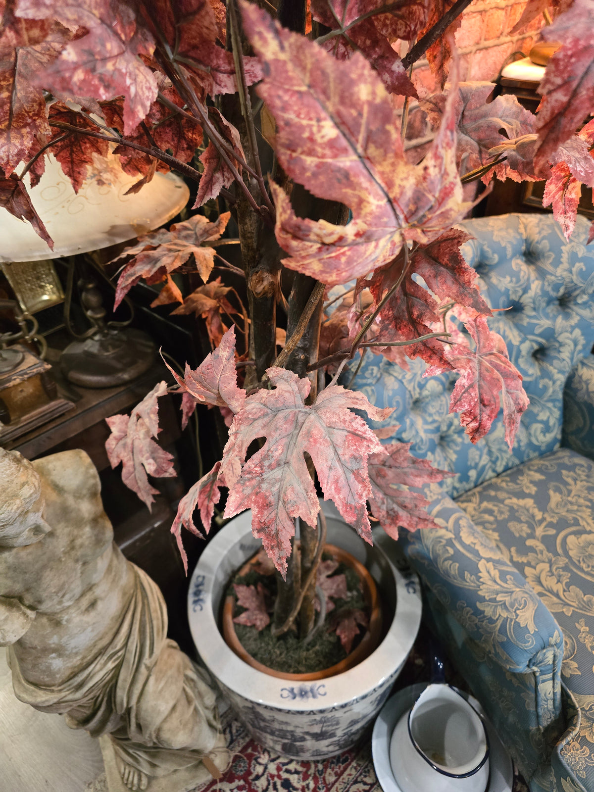 Artificial maple tree with maroon autumn-colored foliage with , blue-and-white porcelain cache-pot