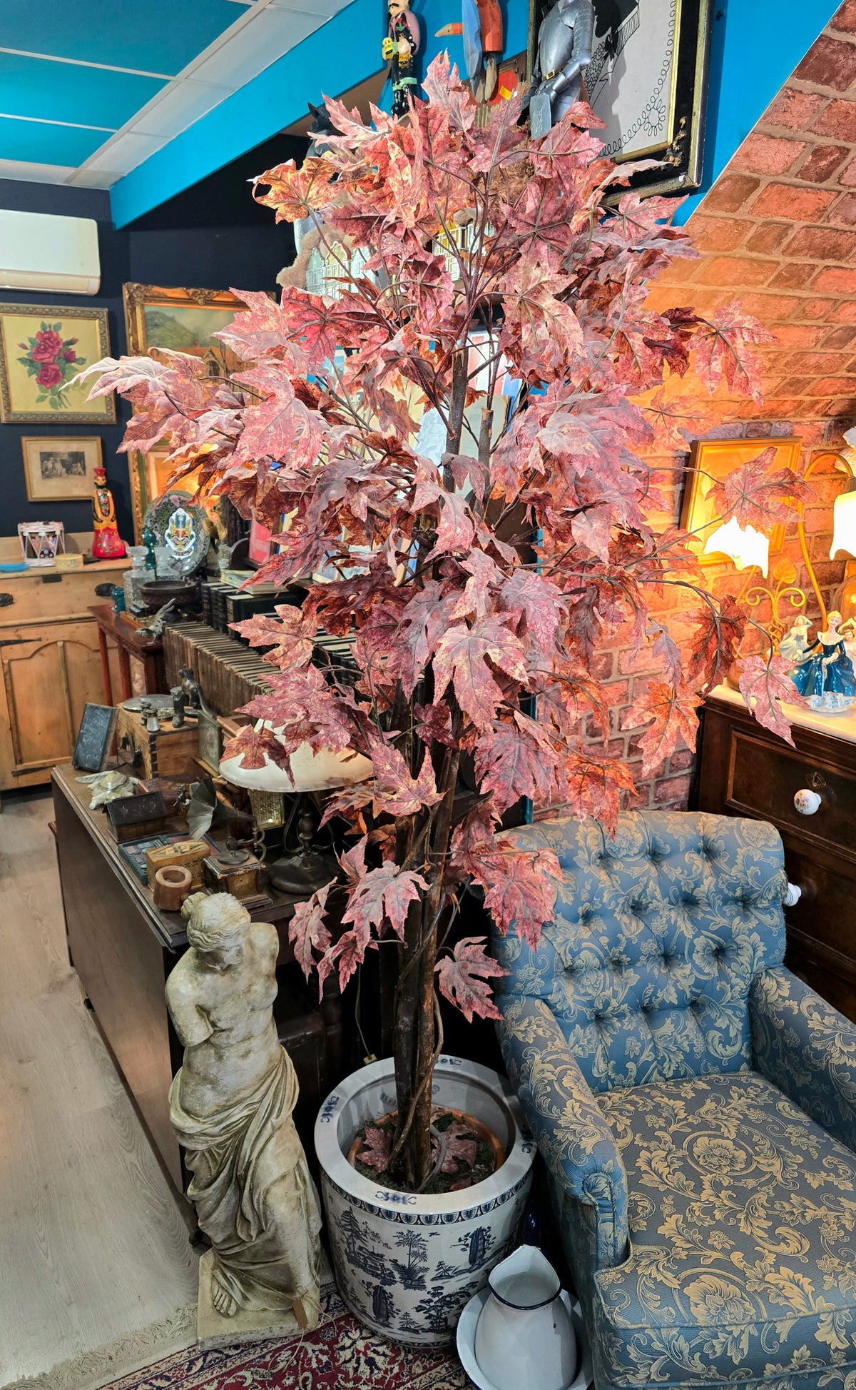 Artificial maple tree with maroon autumn-colored foliage with , blue-and-white porcelain cache-pot
